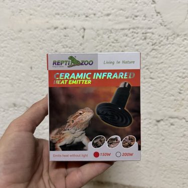 יד יד מחזיקה קופסת חימום קרמי אינפרא אדום לזוחלים, עם לטאה וגוף חימום בתמונה.