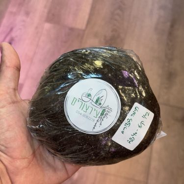 כף יד אוחזת חומר דשן אדמה שחור עטוף בניילון עם מדבקות.